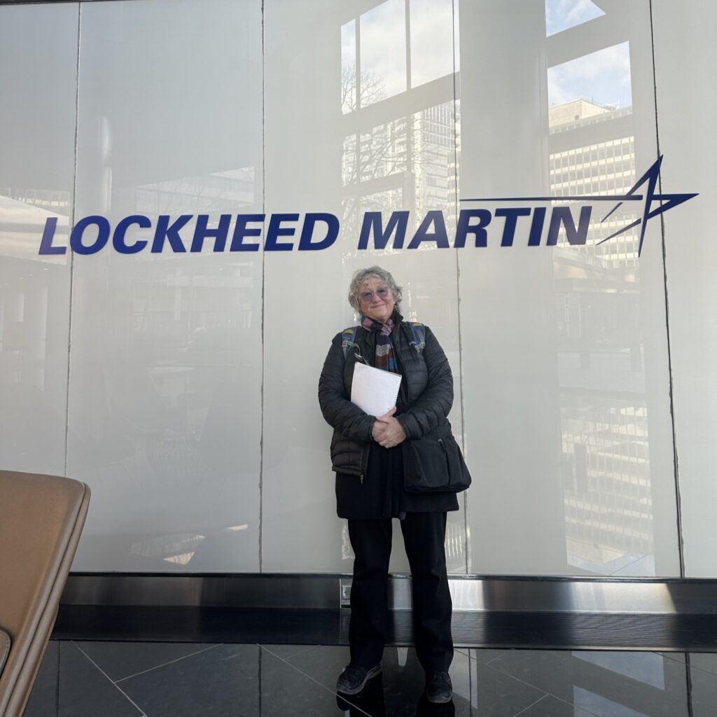 Photo of Vicki Elson standing in front of a Lockheed Martin logo